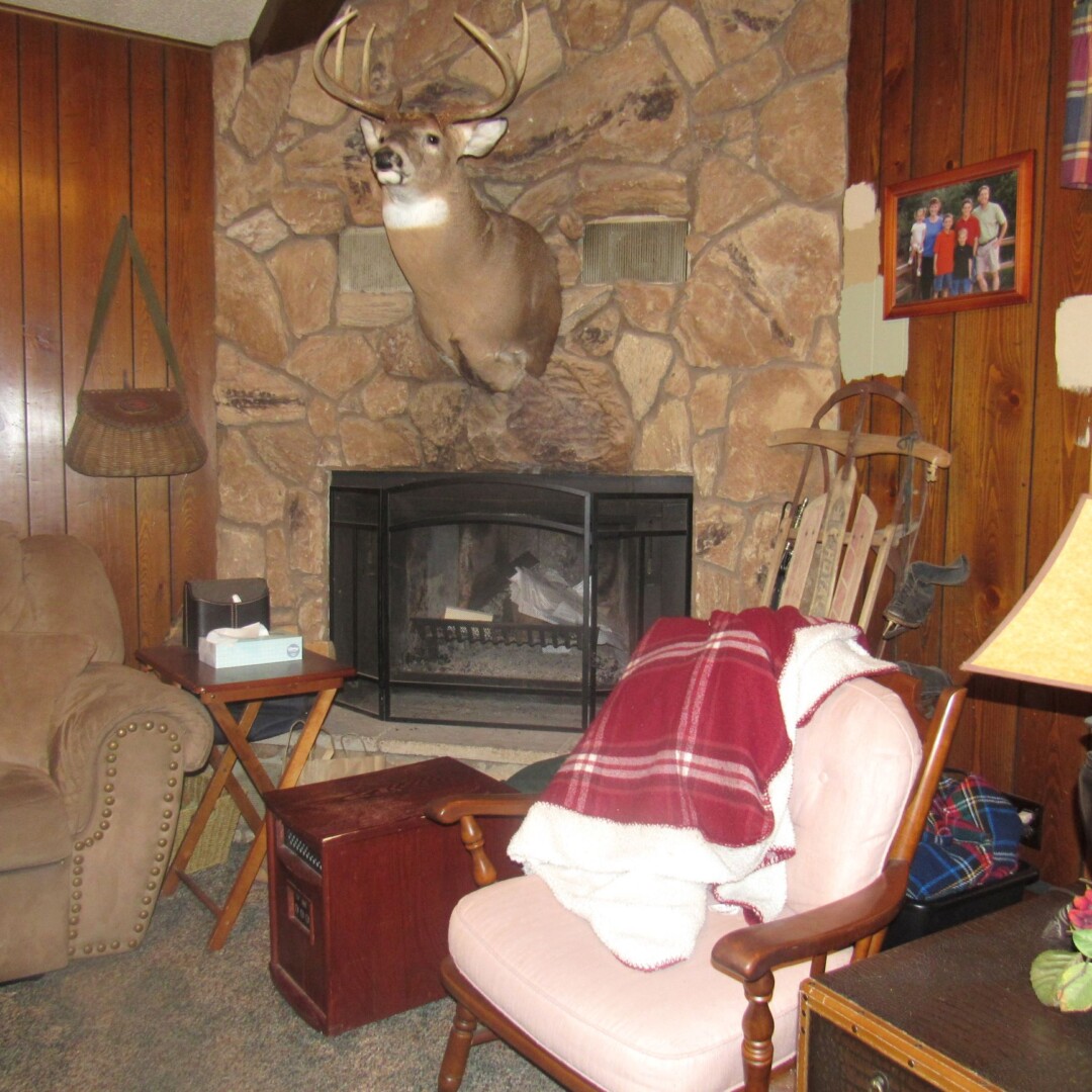 Cabin-like family room with dark paneled walls and deer head appeal to a small range of buyers.