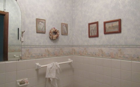 Powder room with dated wallpaper draws attention to the home's lack of upkeep.