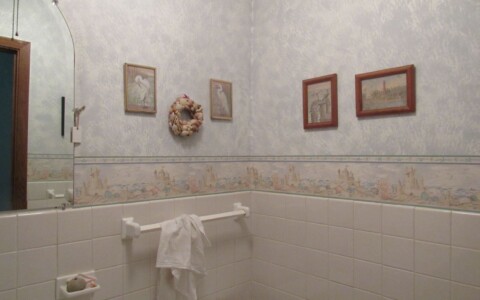 Powder room with dated wallpaper draws attention to the home's lack of upkeep.