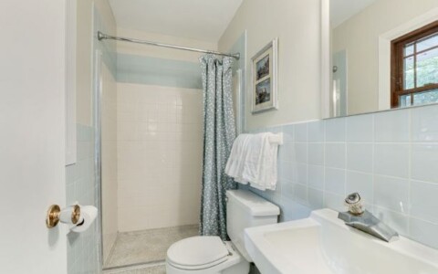 Show buyers they can work with the dated tile color. Add clean, white towels and a fresh curtain that compliments the dated tile color. Lovely and attractive.
